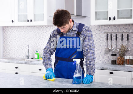 Close-up Of A Young Man Cleaning Dirty Kitchen Counter With Napkin Stock Photo