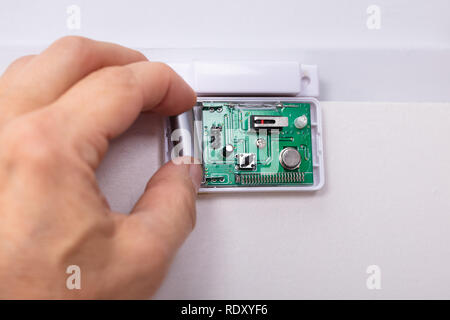 Close-up Of A Technician's Hand Fixing Security System Door Sensor Stock Photo