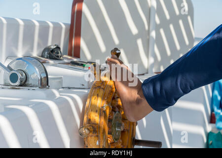 People at the helm of a white yacht. A man Arab controls the yacht. Foot on the yacht steering wheel Stock Photo