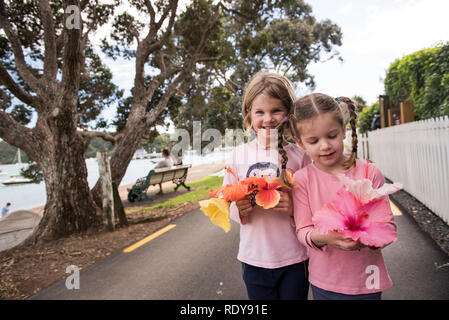 Two young model released sisters pose with flowers they picked while on holiday in the charming town of Russell. Stock Photo