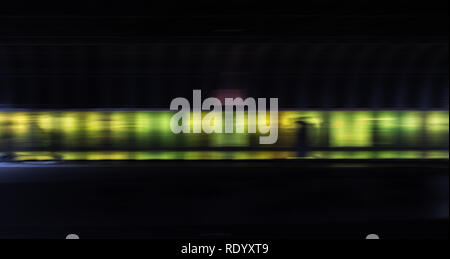 Pedestrians in the tunnel in front of a neon colored wall Stock Photo