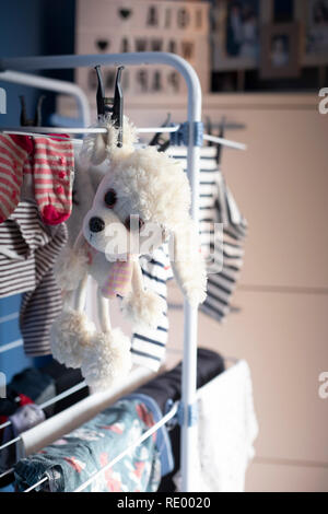 white dog plush toy hanging dry with laundry clothes after being washed. Vertical shot, copyspace. Stock Photo