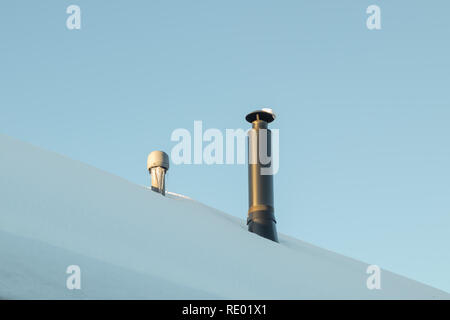 Two chimneys on the snow-covered roof. Stock Photo