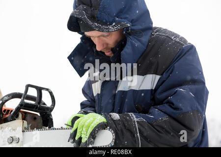 A manual file worker sharpens a chainsaw chain Stock Photo