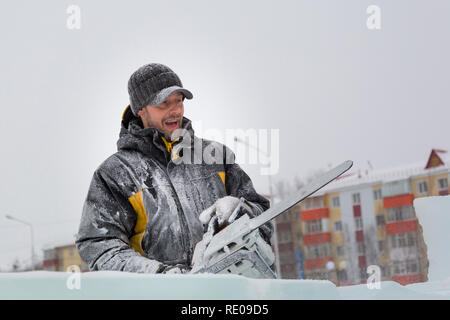 Worker with a chainsaw in hand at the assembly site of the ice town Stock Photo