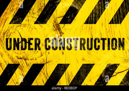 Under construction warning sign text with yellow black stripes painted on wood wall plank texture wide background. Concept do not enter the area, caut Stock Photo