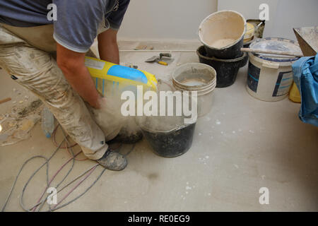 The builder pours the contents of the bag into the bucket. Stock Photo