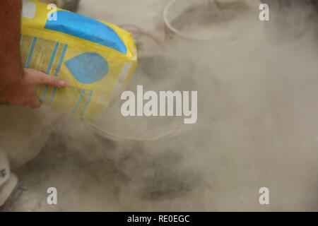 The builder pours the contents of the bag into the bucket. Stock Photo