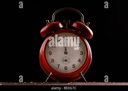 Red retro alarm clock on a dark background. Close-up. Stock Photo