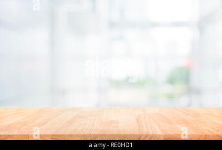 Wood table top on blur white glass wall background form office building.For montage product display and design key visual layout Stock Photo