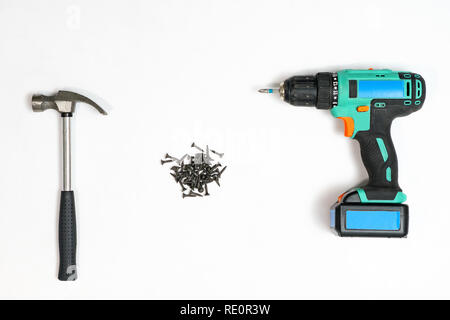 Top view of arranged drill with screwdrivers and pile of nails on white background Stock Photo