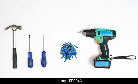 Top view of arranged drill with screwdrivers and hammer with pile of nails on white background Stock Photo