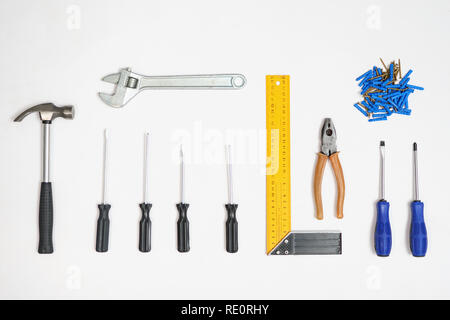 Flat lay of arranged screwdrivers with various tools and dowels with nails on white background Stock Photo