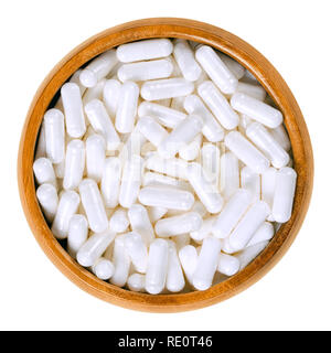 White food supplement capsules in wooden bowl. Hard shelled capsules, filled with powder, for example vitamin B12, cobalamin. Stock Photo