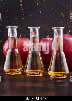 Aged apple brandy or Calvados and red apples, on a dark wooden board, with a dark brown background Stock Photo