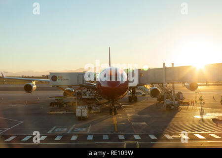 Early morning dawn arrival of Edelweiss airplane at Cape Town International Airport with sunburst and flare. Personnel on the ground Stock Photo