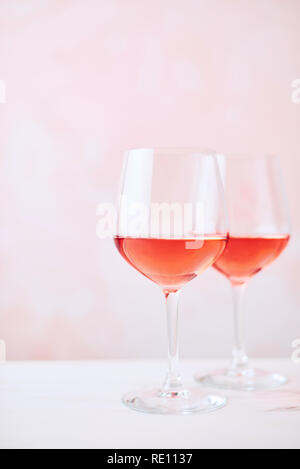 Summer drink. Glass of rose wine on white marble table over pink background with copy space for text. Selective focus. Stock Photo