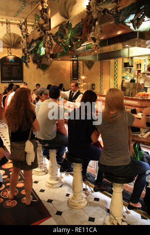 People sitting on bar stools at a seafood and fish restaurant inside of the Harrods department store in London, United Kingdom Stock Photo
