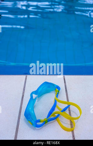 Swimming Goggles on the edge of a swimming pool. Stock Photo