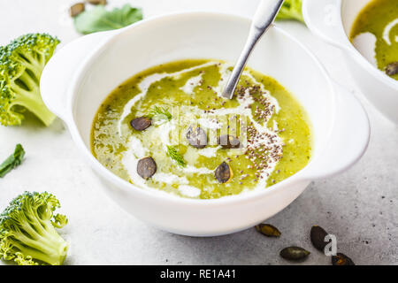 Vegan detox broccoli cream soup with coconut cream and pumpkin seeds in a white bowl. Plant based food concept. Stock Photo