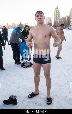 Young man swimming in the winter lake 