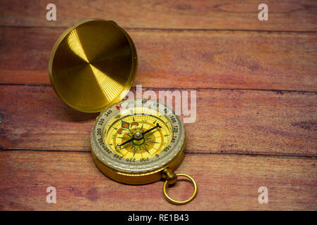 An old compass on a brown wooden table Stock Photo