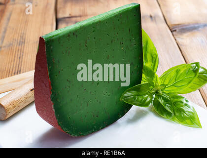 Cheese collection, piece of Dutch green pesto hard cheese with fresh basil close up Stock Photo