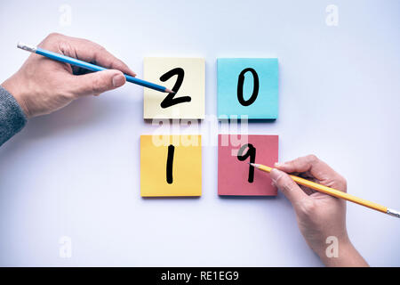 2019 text with male and female hand writing pencil on notepaper color background.business brainstorming  and creativity idea concepts Stock Photo