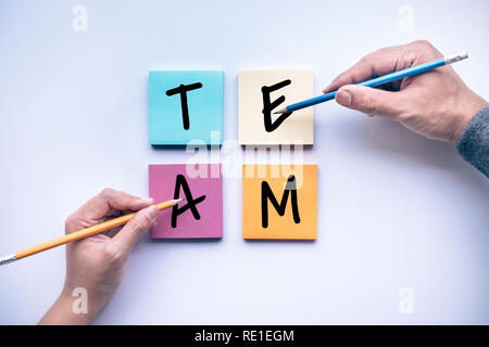 Male and female hand with pencil and team text on notepaper color background.business brainstorming  and creativity idea concepts Stock Photo