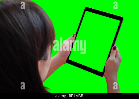 Woman play game or watching video on tablet. Isolated background and screen in green. View over the shoulder. Stock Photo