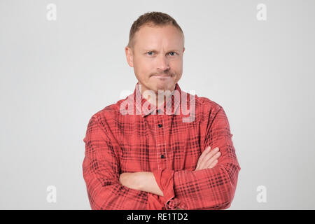 Grumpy mature european man posing in studio with arms folded Stock Photo