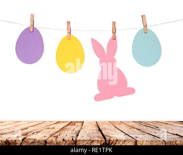 Wooden table and eggs and rabbits decoration garland on white wall. Easter holiday background Stock Photo