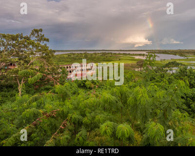 Iquitos, Peru- March 28, 2018: Sunset. View of a rusty boat, raibow and the Itaya river in center of  Iquitos, Loreto, Peru.  Amazon Stock Photo