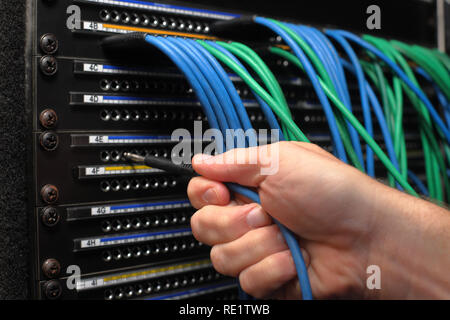 Hand inserting patch cables into Broadcast audio and studio patch panel Stock Photo