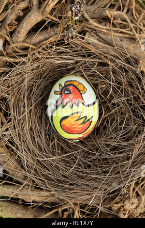 Chicken bird painted on an Easter egg placed in birds nest. Stock Photo