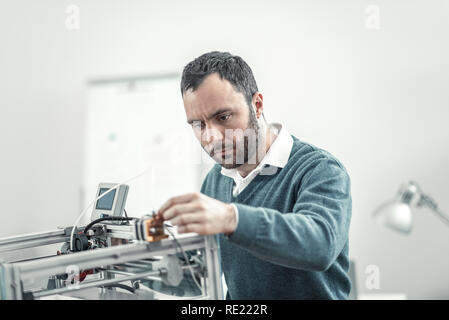 Serious smart adult technician fixing 3d printer Stock Photo