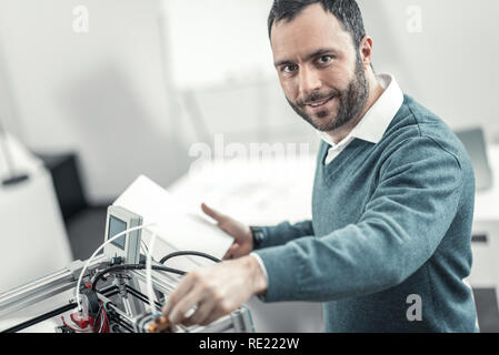 Delighted smart adult technician checking 3d printer Stock Photo