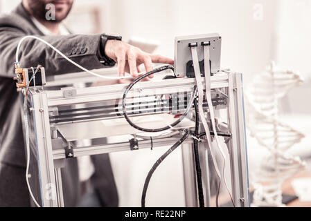 Closeup of mans hand adjusting professional 3D printer Stock Photo