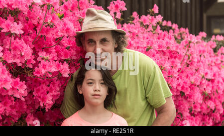 Father and daughter standing in front of pink azaleas Stock Photo