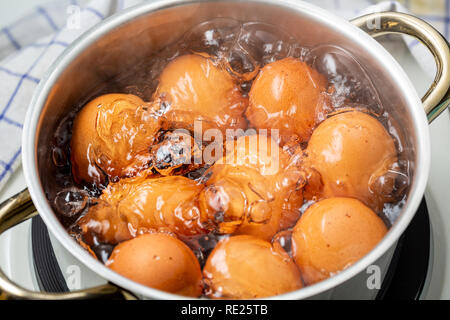 cooking brown chicken eggs in boiling water on electric stove, closeup, elevated view Stock Photo