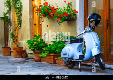 Gorgeous cute decorated street with flowers and rustic entrance, old fashioned scooter standing in typical Italian street, Pienza, Tuscany, Europe Stock Photo