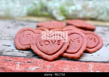 Pink Heart shaped home baked Valentine Day cookies with the word love on them Stock Photo