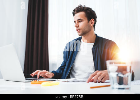 Concentrated manager working on laptop and reading information in modern spale office. Businessman sits at her desk and preparing project Stock Photo