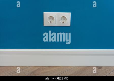 European standard 220 volt wall electrical outlet on wall with baseboard and hardwood floor. Stock Photo