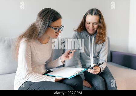 Young woman professional psychotherapist talking with teen girl in office. Mental health of child in adolescence. Stock Photo