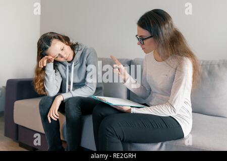 Young woman professional psychologist talking with teenager girl 14, 15 years old sitting in office on sofa. Mental health of child in adolescence. Stock Photo