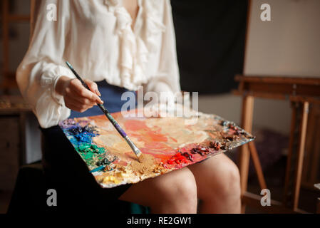 Female painter holds color palette and brush in studio. Creative ...