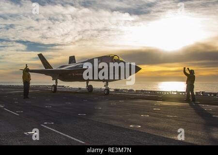 PACIFIC OCEAN (Nov. 7, 2016)  Two Aircraft Maintenance Officers use hand signals to direct an F-35B Lightning II aircraft forward on the flight deck in preparation for launching off the amphibious assault ship USS America (LHA 6). During the third and final F-35B developmental test phase (DT-III), the aircraft is undergoing envelope expansion via a series of launches and recoveries in various operating conditions such as high sea states and high winds. Stock Photo