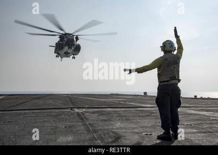 ARABIAN GULF (Nov. 17, 2016) Petty Officer 3rd Class Joshua Broadbent signals to an MH-53E Sea Dragon helicopter assigned to the Blackhawks of Helicopter Mine Countermeasures Squadron (HM) 15 on the flight deck of the aircraft carrier USS Dwight D. Eisenhower (CVN 69). Broadbent serves aboard the ship as an aviation boatswain's mate (handling). Eisenhower and its carrier strike group are deployed in support of Operation Inherent Resolve, maritime security operations and theater security cooperation efforts in the U.S. 5th Fleet area of operations. Stock Photo