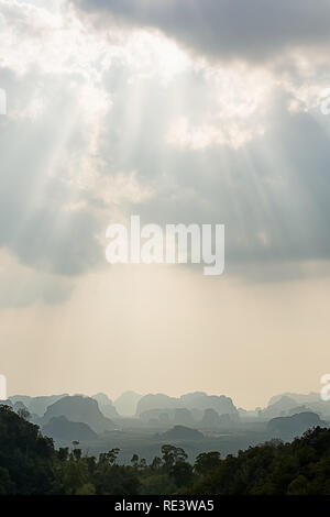 Portrait landscape of Limestone hills of the landscape around Krabi, Thailand with sun rays bursting through the clouds. Stock Photo